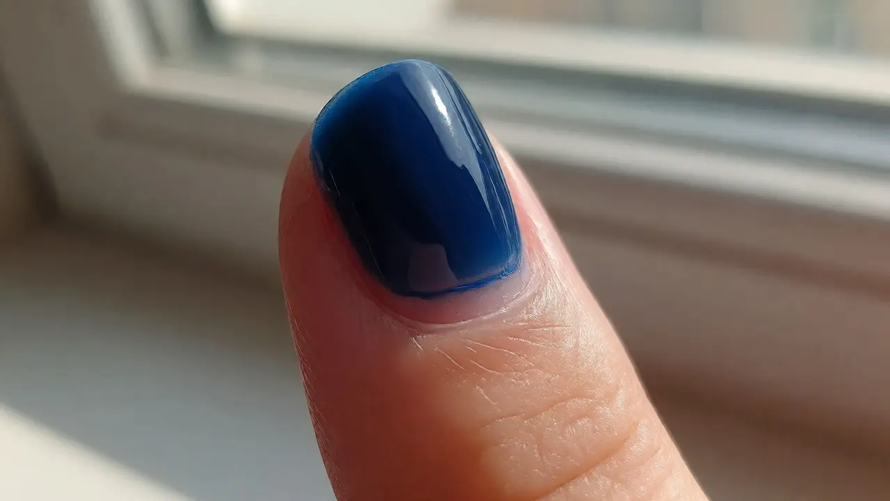 Detail nehtu viditelný odrost u kožičky pod tmavě modrým gelem